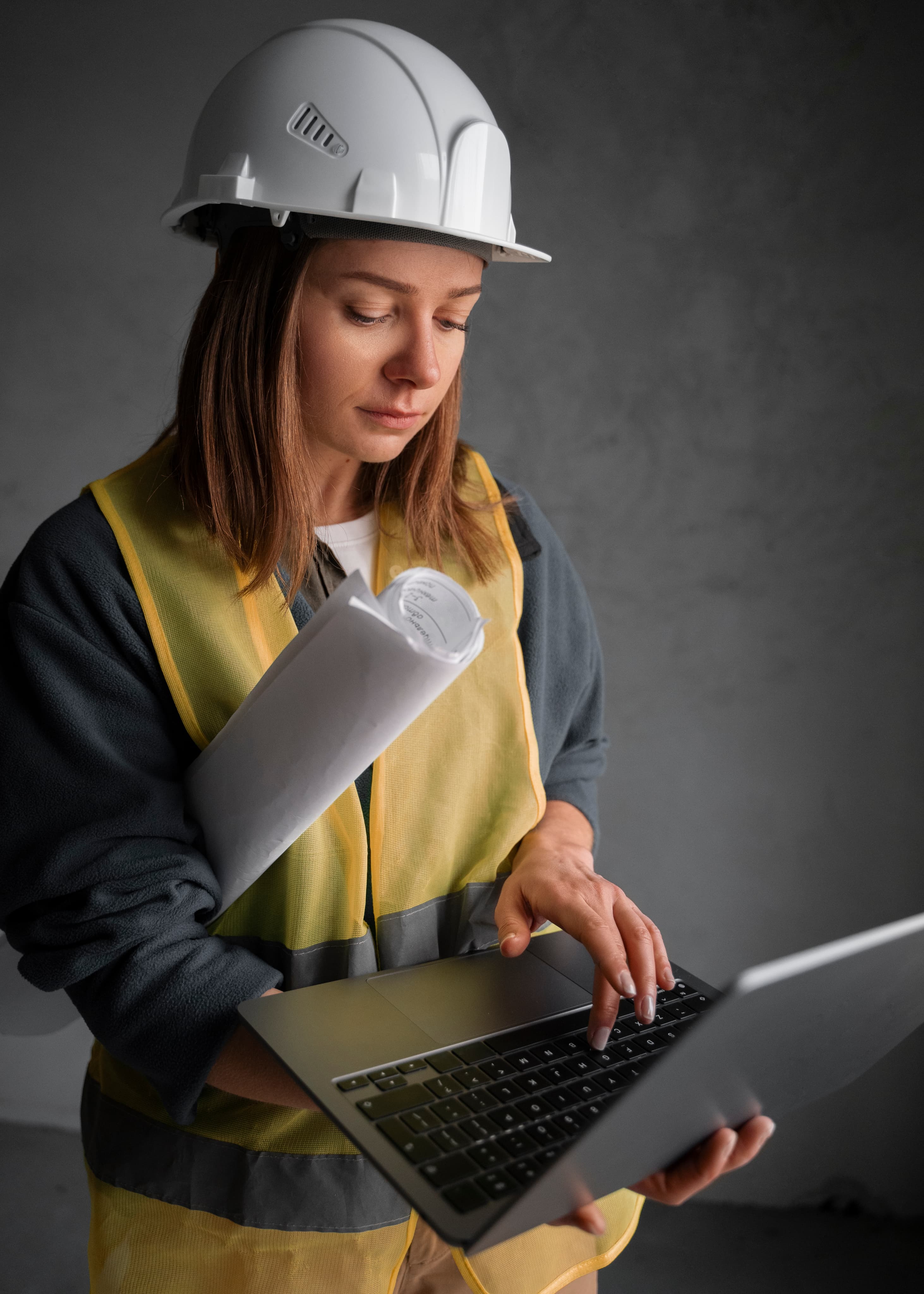 Contractor in hard hat and safety vest using a laptop to access features available through Aurora Home Hardware Building Centre PRO Services.