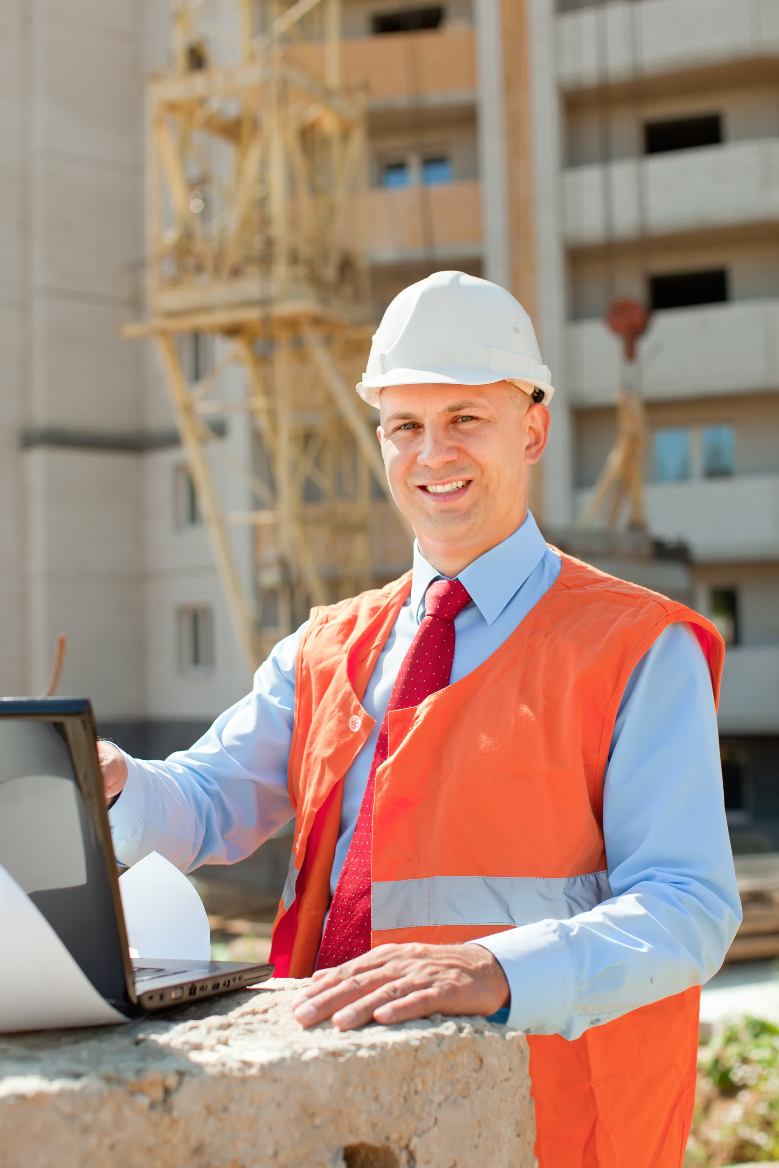 Contractor in hard hat and safety vest using a laptop on a job site accessing Aurora Home Hardware Building Centre PRO Services.