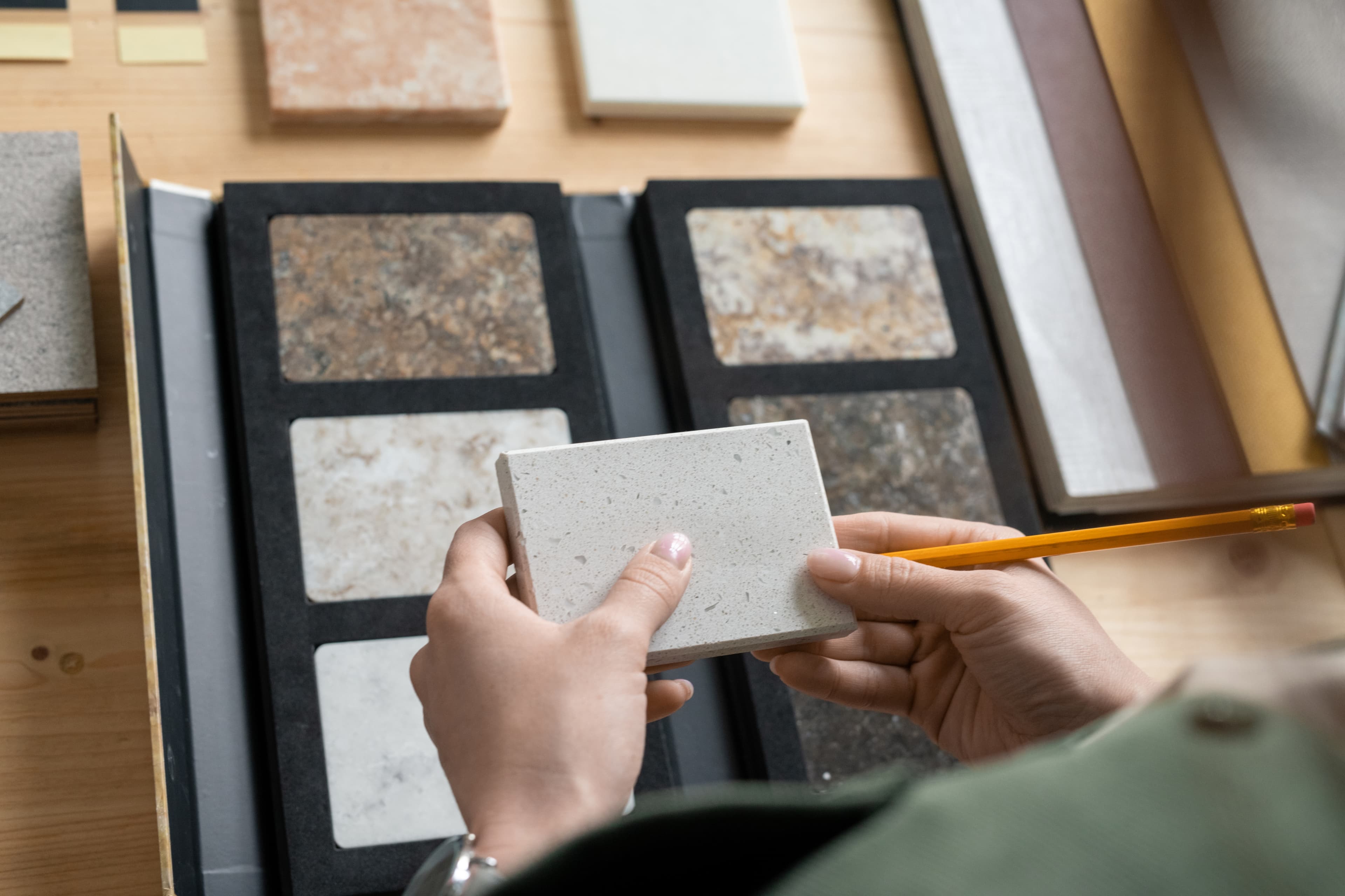 A hand selecting deck material samples from a swatch book for the custom deck design service at Aurora Home Hardware Building Centre.