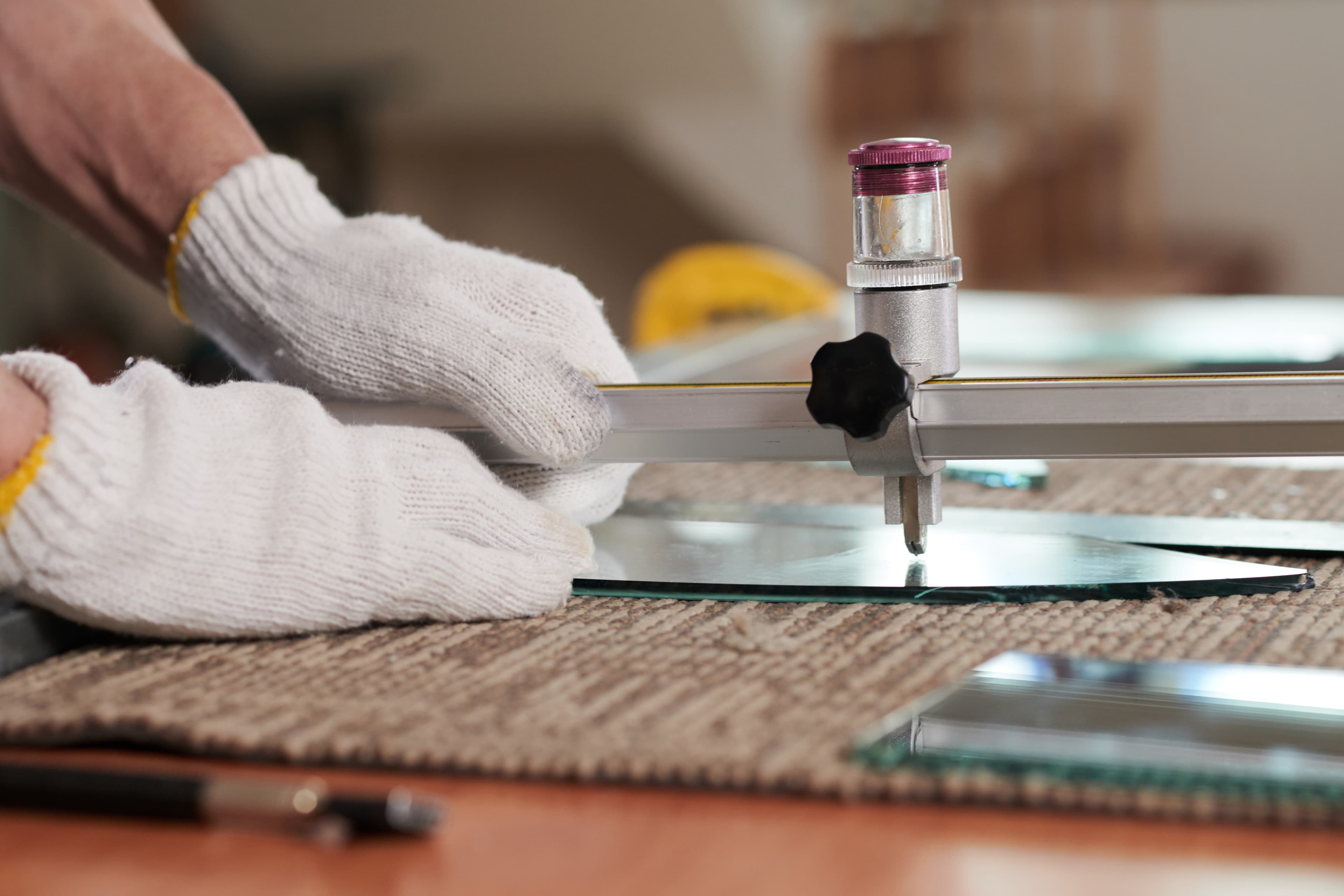 Hands cutting glass to size with a precision tool at Aurora Home Hardware Building Centre.